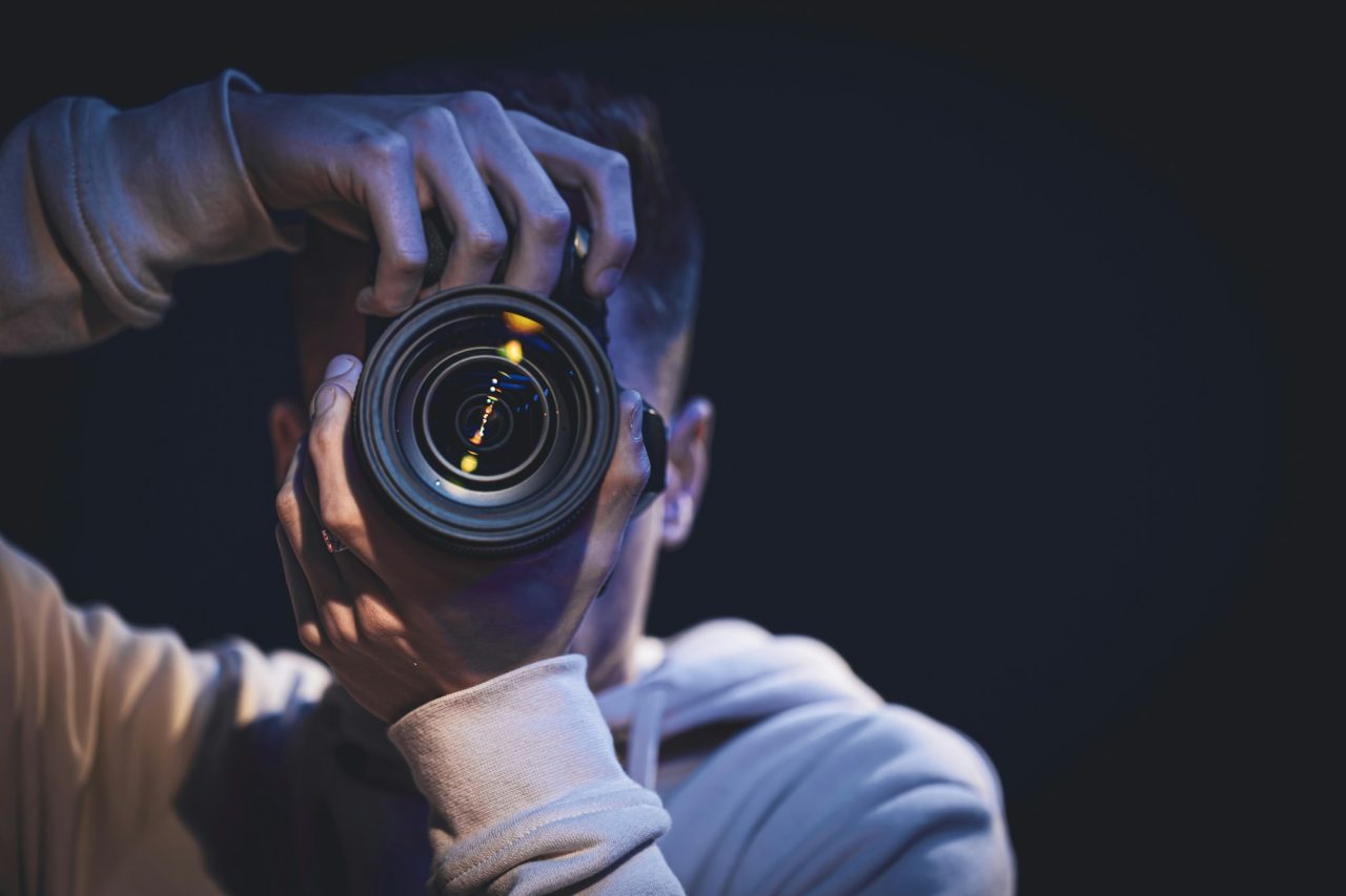 A man photographer with a camera takes a photo in the dark space
