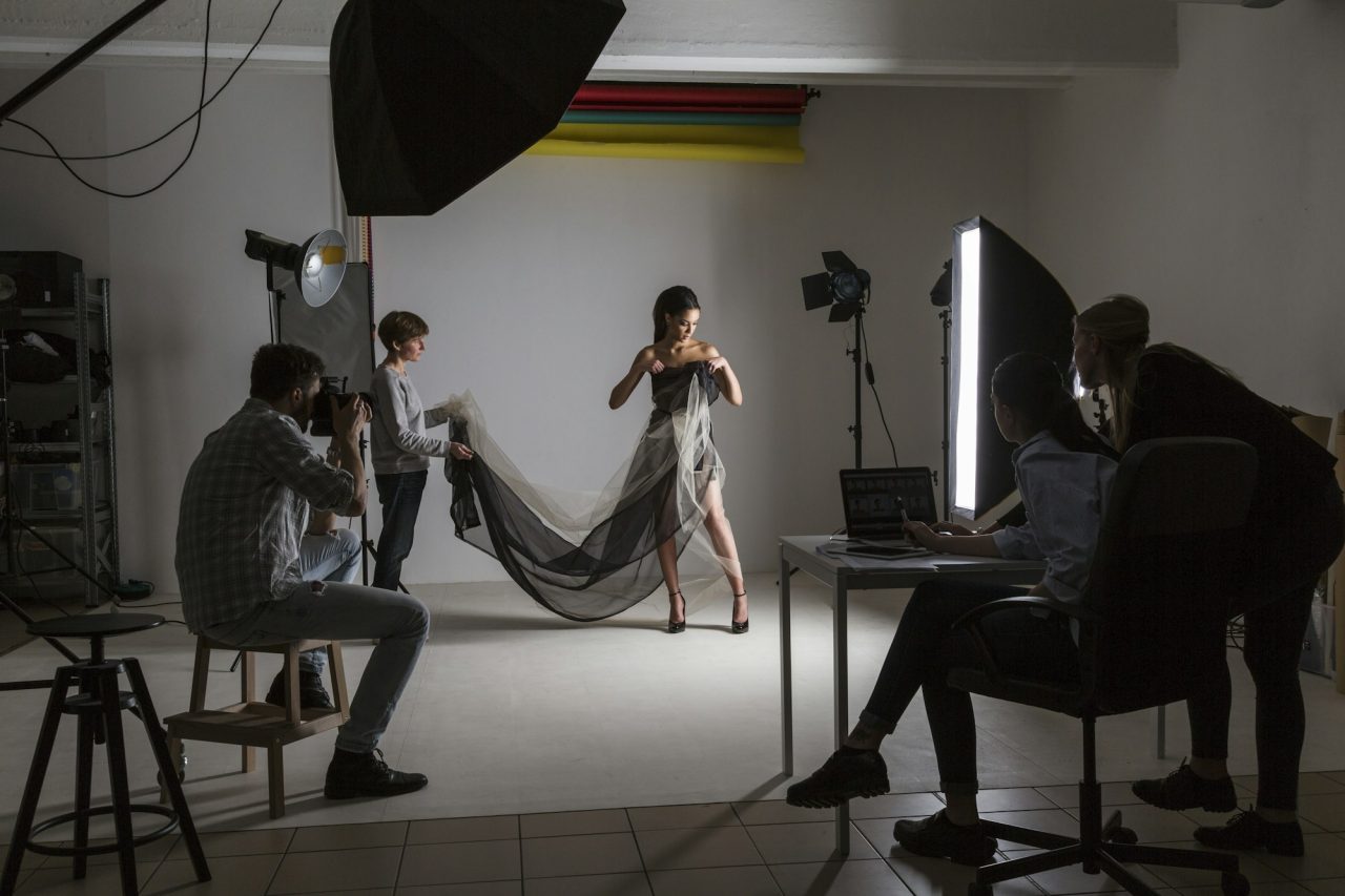 Photography team and model in low key photography studio shoot